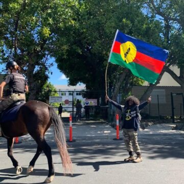 Un habitant agite le drapeau kanak au passage d’un agent de la gendarmerie montée dans le sillage des manifestations contre le dégel du corps électoral. Nouvelle-Calédonie, 11 mai 2024. Photo : DR