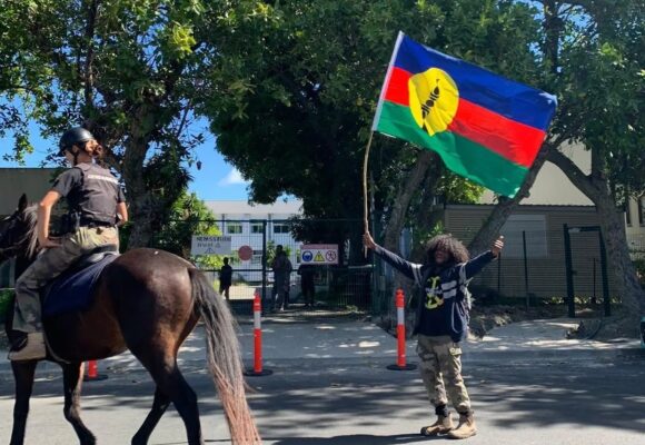 Un habitant agite le drapeau kanak au passage d’un agent de la gendarmerie montée dans le sillage des manifestations contre le dégel du corps électoral. Nouvelle-Calédonie, 11 mai 2024. Photo : DR