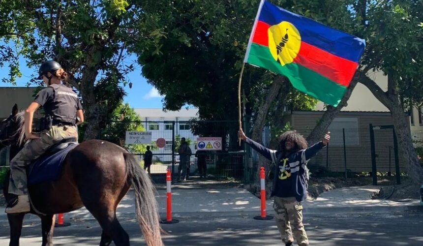 Un habitant agite le drapeau kanak au passage d’un agent de la gendarmerie montée dans le sillage des manifestations contre le dégel du corps électoral. Nouvelle-Calédonie, 11 mai 2024. Photo : DR