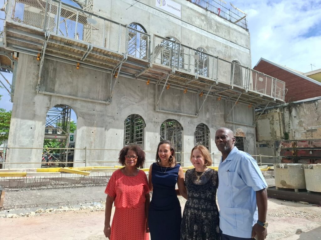 De droite à gauche : Harry Durimel, maire de Pointe-à-Pitre, Lorraine Carrady, présidente de Caribbean cinemas, Christelle Galou directrice du Cinestar by Caribbean cinemas des Abymes, Francesca Faithful vice-présidente de Cap excellence. Devant le chantier de reconstruction du cinéma Renaissance et sa façade art déco d’entre-deux-guerres qui retrouvera ses motifs spirales et ses ornements géométriques. Pointe-à-Pitre, le 19 février 2025. Photo : FB Communauté d'Agglomération Cap Excellence