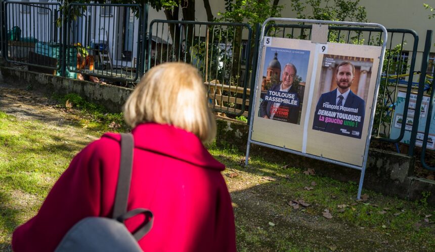Toulouse, 20 mars 2026. Une personne regarde les panneaux électoraux en vue du second tour des élections municipales le 22 mars 2026 avec l’actuel Maire de Toulouse Jean Luc Moudenc (G) et Francois Piquemal pour LFI (D). Photo : Frédéric Scheiber / Hans Lucas via AFP